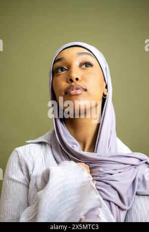 Porträt einer jungen Frau im Hijab vor grünem Hintergrund Stockfoto