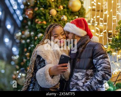 Ein lächelndes Paar macht Selfie mit Weihnachtsmütze Stockfoto