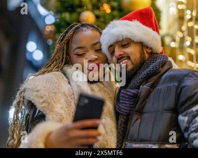 Ein lächelndes Paar macht Selfie mit Weihnachtsmütze Stockfoto