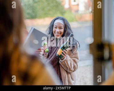 Lächelnde Frau besucht einen Freund im Haus Stockfoto