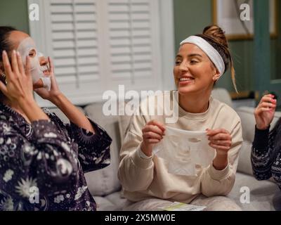 Freunde, die Gesichtsmasken im Wohnzimmer tragen Stockfoto