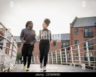 Lächelnder athletischer Mann und Frau, die auf dem Steg joggen Stockfoto