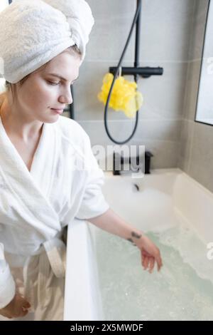 Frau im Handtuchturban, die ein Luftpolsterbad vorbereitet Stockfoto