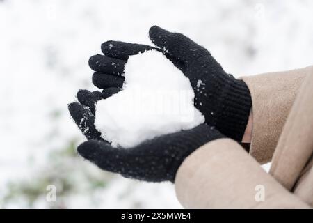 Nahaufnahme von Handschuhen, die das Schneeherz halten Stockfoto