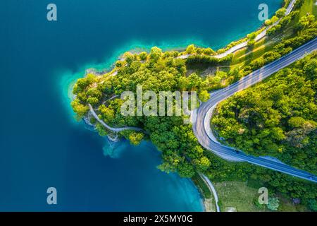 Blick aus der Vogelperspektive auf den Lago di Ledro mit türkisfarbenem Wasser und gewundener Straße, lebhafte Sommerlandschaft in Norditalien, malerische Seeroute Stockfoto