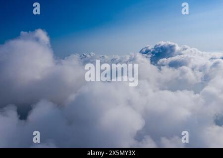 Aus der Vogelperspektive die flauschige Wolkenlandschaft, den ruhigen blauen Himmel und die Cumulus-Wolken aus großer Höhe Stockfoto