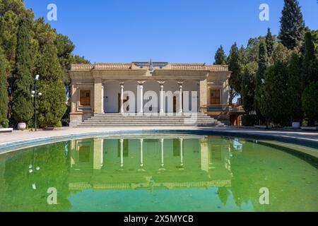 Ein ruhiger Blick auf den zoroastrischen Feuertempel mit dem reflektierenden Pool im Vordergrund. Yazd, Iran, umgeben von Bäumen auf beiden Seiten. Stockfoto