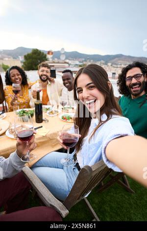 Gruppe mit verschiedenen Freunden, die Spaß auf der Dachparty haben. Schöne Frau, die Selfie beim Barbecue macht. Stockfoto