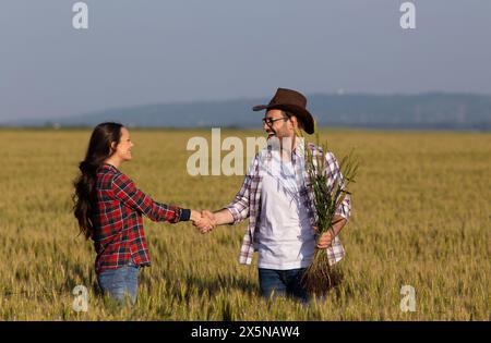 Zwei Bauern, Männer und Frauen, die im Sommer auf dem Weizenfeld die Hand schütteln und in der Agrarwirtschaft handeln Stockfoto