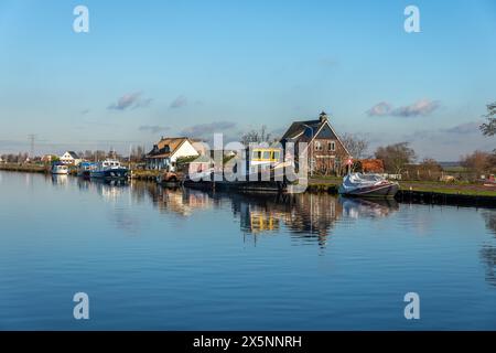 Reflexion im Wasser verschiedener Motoryachten auf der Ringvaart auf der Lisserdijk im Dorf Buitenkaag in Noord-Holland in den Niederlanden. Stockfoto