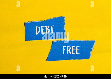 Schuldenfreie Wörter auf gerissenen blauen Papierstücken mit gelbem Hintergrund. Konzeptionelles schuldenfreies Symbol. Kopierbereich. Stockfoto