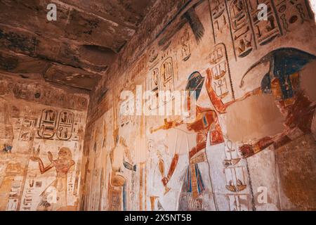 Wandkunst an den Tempelwänden in Medinet Habu, Luxor, Ägypten, mit Szenen von Göttern, Pharaonen und religiösen Ritualen. Stockfoto