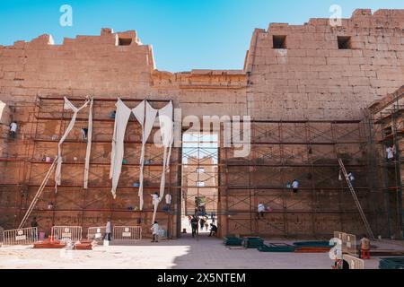 Arbeiter in Labormänteln auf Gerüsten arbeiten an der Restaurierung und Erhaltung der Steinmauern des Tempels in Medinet Habu in Luxor, Ägypten Stockfoto