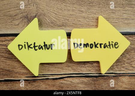 Konzept der Diktatur oder Demokratie in Language Germany Schreiben Sie auf Haftnotizen isoliert auf Holztisch. Stockfoto