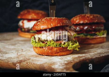 Gourmet-Beef-Burger mit Melty Cheese und frischen Belägen auf einem Holzbrett Stockfoto