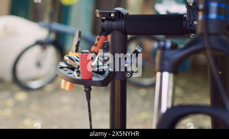 Zoom-Aufnahme mit klarer Sicht auf die professionelle Ausrüstung, die auf dem Reparaturstand angezeigt wird, zeigt die Bereitschaft zur Fahrradwartung im Freien an. Verschiedene spezielle Arbeitsgeräte auf dem Fahrradständer. Stockfoto