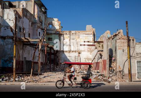 Das Trettaxi passiert das eingestürzte Gebäude in der Innenstadt von Havanna, Kuba Stockfoto