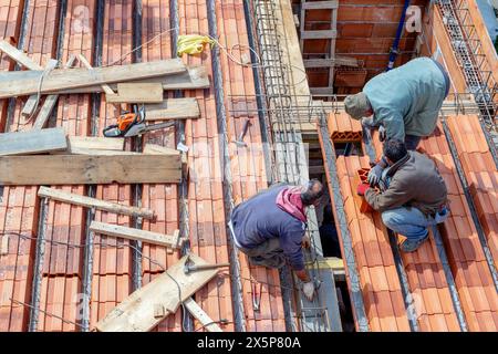 Bauarbeiter bereiten ein Stahlgitter vor, um eine Verlängerung der Dachplatte zu verstärken, bevor sie eine Betonmischung gießen. Stockfoto