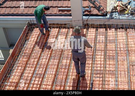 Bauarbeiter bereiten ein Stahlgitter vor, um eine Verlängerung der Dachplatte zu verstärken, bevor sie eine Betonmischung gießen. Stockfoto