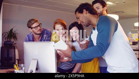 Freunde, einschließlich kaukasischer und birassischer Kollegen, schauen sich einen Computer an Stockfoto