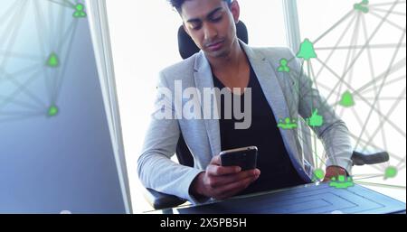 Bild von verbundenen Symbolen über birassischen Männern, die im Büro auf dem Smartphone scrollen Stockfoto
