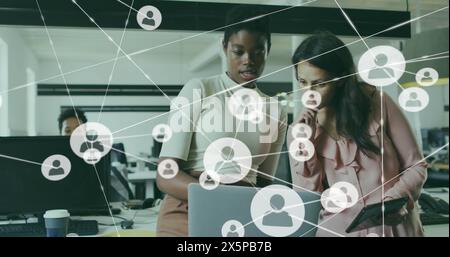 Bild von verbundenen Symbolen über verschiedenen weiblichen Kollegen, die Berichte auf einem Laptop analysieren Stockfoto