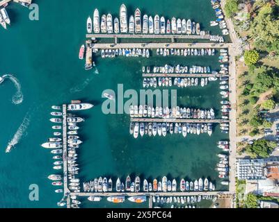 Luftaufnahme von oben nach unten von Bootsanlegestelle und Yachthafen in Budva, Montenegro. Weiße private Motorboote werden an der adriatischen Küste an der Anlegestelle vertäut. Yachtclub Stockfoto