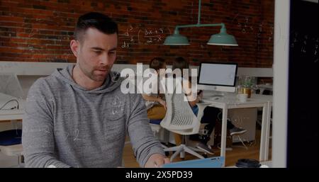 Bild mathematischer Gleichungen über kaukasier, der im Büro über Laptop arbeitet Stockfoto