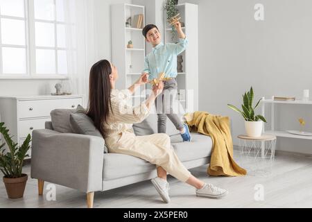 Mutter und ihr kleiner Sohn spielen zu Hause mit Spielzeugflugzeugen Stockfoto