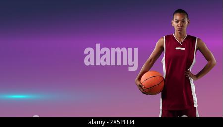 Bild eines weiblichen Basketballspielers, der den Ball über einem leuchtend rosa Hintergrund hält Stockfoto