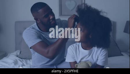 Afroamerikanischer Vater/älterer Bruder, der die Haare einer kleinen Tochter im Bett bindet Stockfoto