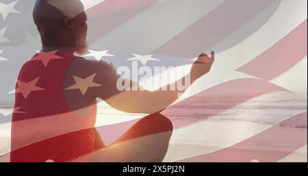 Bild der Flagge der usa über einem ranghohen afroamerikanischen Mann, der Yoga am Strand praktiziert Stockfoto