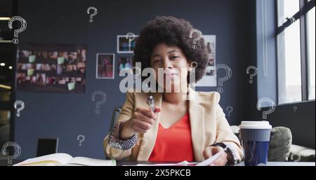 Bild des Fragezeichensymbols über birassischer Geschäftsfrau mit Afro-Haarschrift im Buch Stockfoto