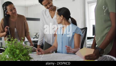 Bild von Fragezeichen über multirassischen Kollegen, die in einer Besprechung im Büro diskutieren Stockfoto
