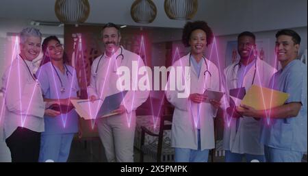 Bild des Herzfrequenzmessgeräts über einem Team von verschiedenen Ärzten und Gesundheitspersonal, die im Krankenhaus lächeln Stockfoto
