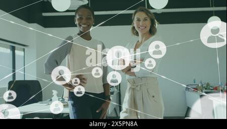 Bild von Symbolen, die mit Linien über lächelnden Kollegen verbunden sind, die im Büro stehen Stockfoto