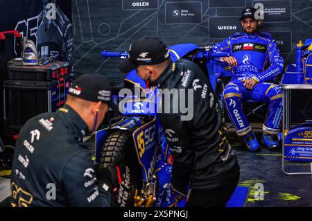 Der polnische Fahrer und aktuelle Weltmeister Bartosz Zmarzlik (R) wartet, während seine Mechaniker sein Motorrad vorbereiten. Am 10. Und 11. Mai 2024 hält der FIM Speedway Grand Prix in Warschau, Polen, im Stadion Narodowy. Während das Hauptereignis am Samstag, den 11. Mai, stattfindet, nehmen die Fahrer am Qualifying Teil, das in einem geschichtsträchtigen 1. SGP-Sprint-Rennen aller Zeiten gipfelt. Der britische Fahrer Dan Bewley überholte den dänischen Star Leon Madsen, um den Sprint zu gewinnen und erzielte sich 4 Weltmeisterschaftspunkte. Stockfoto