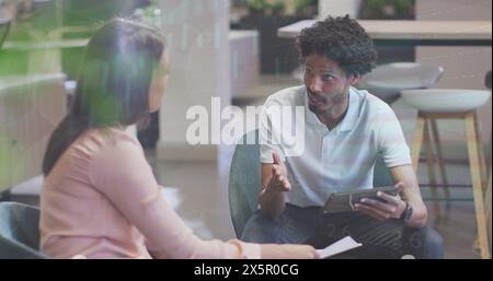 Ein vielseitiges Paar diskutiert, ein Mann hält ein Tablet Stockfoto