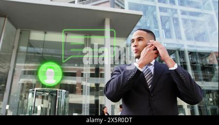 Ein junger, birassischer Mann im Anzug, der auf einem Smartphone vor dem Bürogebäude spricht Stockfoto