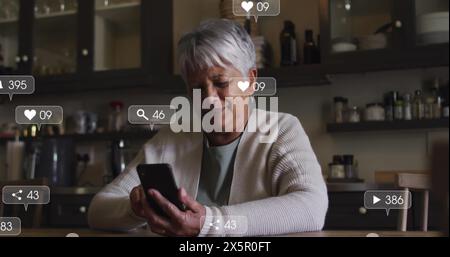Ältere birassische Frau mit grauem Haar, die auf das Smartphone schaut Stockfoto