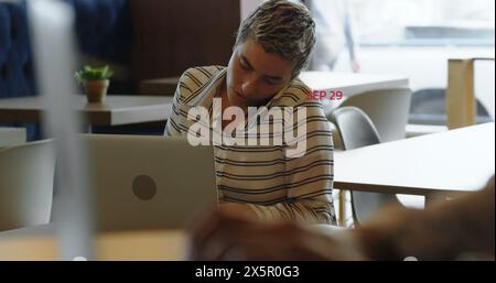 Kaukasische Frau sitzt am Tisch und konzentriert sich auf einen Laptop Stockfoto