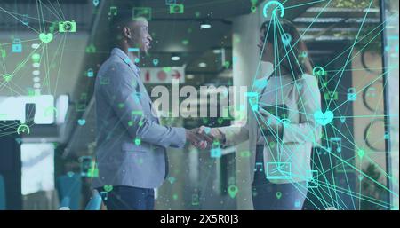 Bild von vernetzten Ikonen, die Kugeln über verschiedenen Geschäftsleuten bilden, die im Büro die Hand schütteln Stockfoto