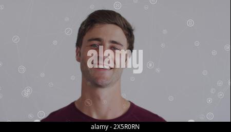 Bild eines Netzwerks von Verbindungen mit Ikonen über dem kaukasischen Mann, der in die Kamera lächelt Stockfoto