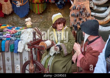 Baiona, Pontevedra, Galicien, Spanien; März, 04.2023; ein Handwerker mit einem drehenden Rad schaut auf einen anderen Handwerker auf dem mittelalterlichen Festival von Stockfoto