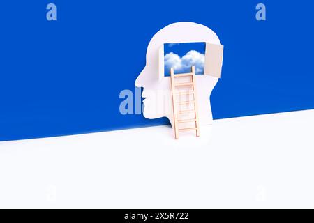 Miniatur-Komposition aus einem männlichen Kopf Papierausschnitt mit einer Holzleiter, die zum offenen Fenster im Gedankenbereich führt, zeigt driftende Wolken. Co Stockfoto