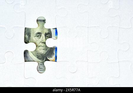Nahaufnahme eines Puzzles mit Löchern, die Elemente eines US-Dollarbetrags enthüllen. Finanzplanung, harte Arbeit und Investitionskonzept. Stockfoto
