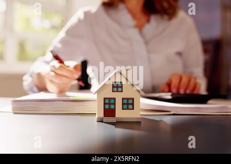 Person Hand Tun Immobilien Steuerberechnung Mit Rechner Des Hauses Modell Stockfoto