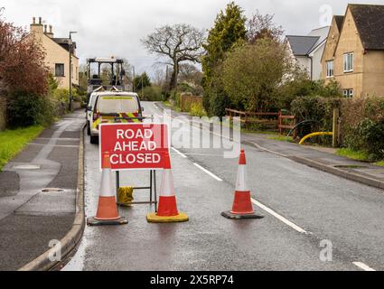 Schild „Road Ahead Closed“ (Straße vor geschlossen) mit Highway Maintenance-Van – Metallweiß auf rotem Text Stockfoto