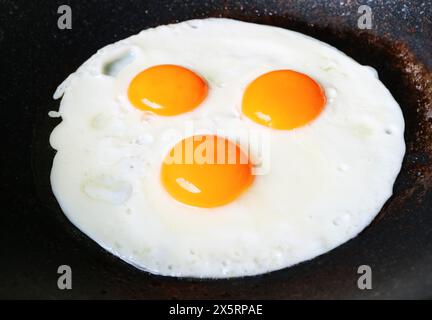 Nahaufnahme von drei Hühnereiern, die in einer Pfanne gebraten wurden Stockfoto
