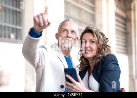 Glückliche Freunde oder Paare, die den Standort auf dem Smartphone auf der Straße überprüfen. Stockfoto